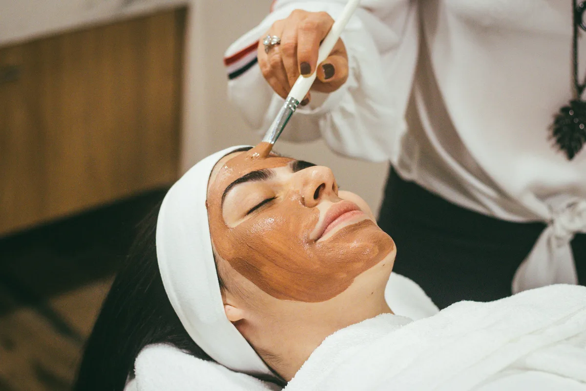 An aesthetician applying a facial treatment to a relaxed client